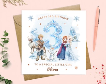 May include: A square birthday greeting card featuring a large blue ice-themed number 3, illustrations of characters including a reindeer, a snowman, and two figures in winter attire, with the text HAPPY 3RD BIRTHDAY, TO A SPECIAL LITTLE GIRL, and Olivia.