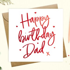 May include: A white card with red lettering that says "Happy birthday Dad" with a red heart and a red "x" at the end. There are small red hearts scattered around the text.