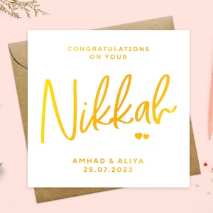May include: White card with gold lettering announcing a Nikkah for Amhad & Aliya on 25.07.2023. The word Nikkah is written in a large, stylized font.