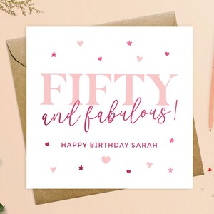 May include: A white card with pink and red hearts and stars. The text on the card reads "FIFTY and fabulous! Happy Birthday Sarah".