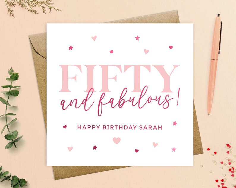 May include: A white card with pink and red hearts and stars. The text on the card reads "FIFTY and fabulous! Happy Birthday Sarah".