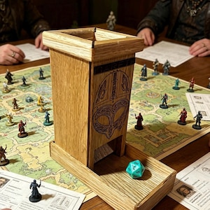 May include: A tall, light-colored wooden dice tower with a square top and a rectangular base tray. The front panel features a dark, engraved Viking-style helmet design and the word GARETH. A single turquoise twenty-sided die sits in the tray.
