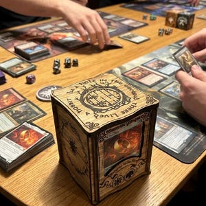 Peut inclure: Boîte de rangement de cartes en bois avec un design gravé au laser, avec du texte et des images sur le thème de la fantaisie. La boîte est sur une table en bois avec des cartes à jouer et des dés. La boîte a une fenêtre transparente montrant une carte.