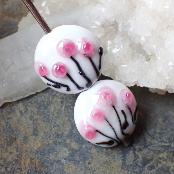 2 perles plates forme lentille  fond blanc avec fleurs roses  en verre de  Murano filé au chalumeau dans mon atelier