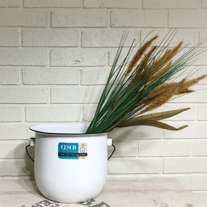 May include: White enamelware pail with a black rim and a blue and white label that reads "CESCO" and "One way Fire-Proofing Enamelware". The pail is filled with dried grass.