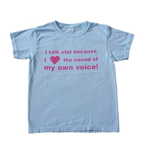 May include: Light blue t-shirt with a pink heart and the text "I talk alot because I ♥ the sound of my own voice!"