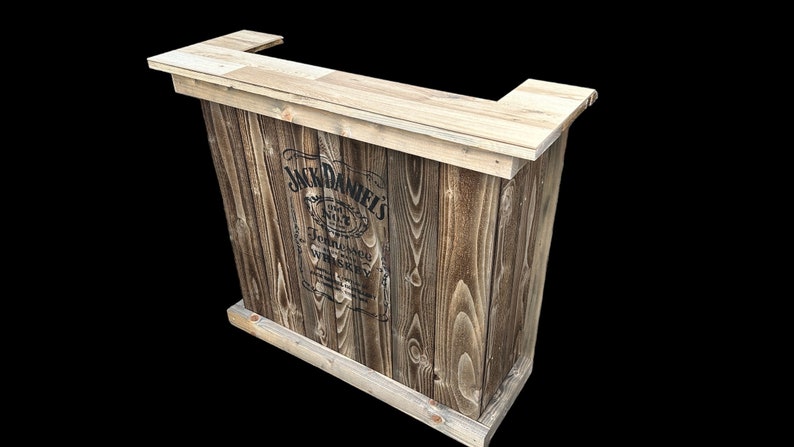 Op de afbeelding: Een houten bartafel met een Jack Daniel's logo gedrukt op de voorkant. De tafel is gemaakt van gerecycled hout en heeft een rustieke afwerking.