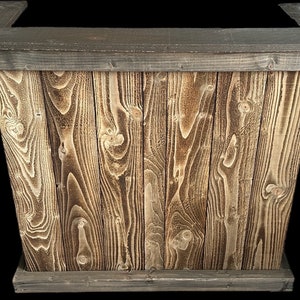 Op de afbeelding: Een rustieke houten bartafel met een donkerbruin gebeitst blad en een lichtbruine houten basis. De tafel is gemaakt van gerecycled hout met een natuurlijke houtnerf.