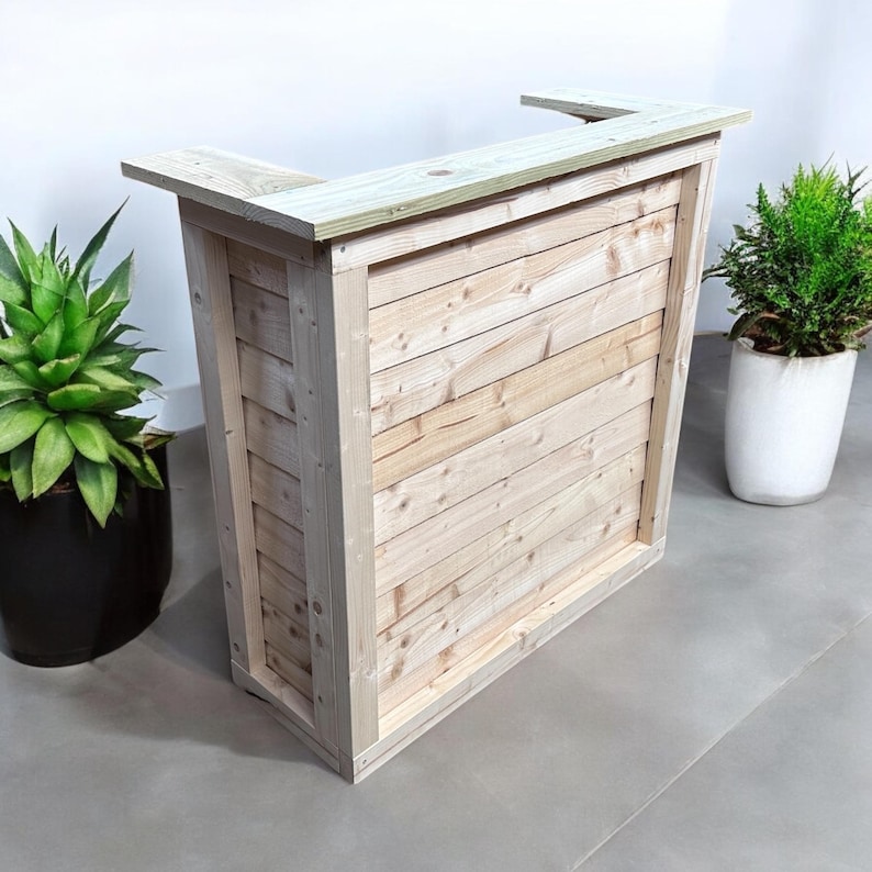 May include: A wooden counter with a natural finish. The counter has a rectangular top and a front panel made of horizontal wooden slats. The counter is standing on a light gray floor.