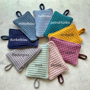 May include: Nine pot holders in various colors, including mint, pink, purple, yellow, blue, and gray. Each pot holder has a waffle-like texture and a loop handle.