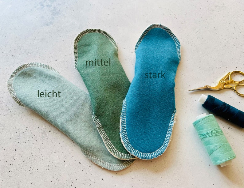 Peut inclure: Trois coussinets en tissu de diff&eacute;rentes nuances de vert et de bleu, &eacute;tiquet&eacute;s "leicht", "mittel" et "stark".