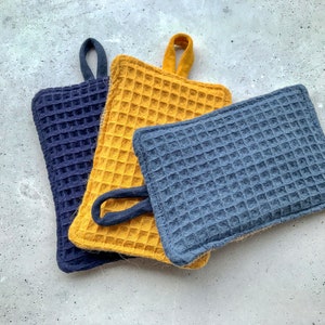 Può includere: Tre presine, una gialla e due blu, con una texture a nido d'ape. Le presine sono realizzate in un materiale morbido e assorbente, ideali per proteggere le mani dalle superfici calde.