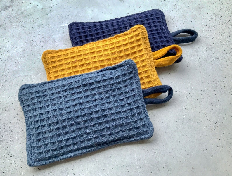 May include: Three waffle weave kitchen pot holders. One is yellow, and two are blue.