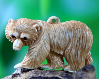 May include: A carved ivory bear figurine with a detailed, textured surface. The bear is standing on a wooden base.