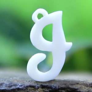 May include: White plastic letter G charm with a cursive font. The charm has a hole at the top for hanging.