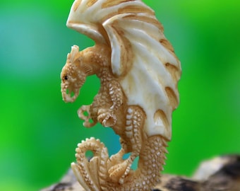 May include: A detailed, ivory-colored dragon figurine with large, textured wings. The dragon is posed with its wings spread, showcasing intricate scale and claw details. The figurine is set against a blurred green background.