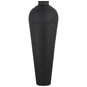 May include: A tall, black vase with a textured, hammered metal finish. The vase has a narrow neck and a wide, elongated body, suitable for displaying decorative branches or flowers. The vase is a decorative home accent.