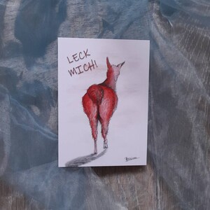 May include: A humorous illustration of a llama from the rear, rendered in shades of red and pink. The text "LECK MICH!" is written above the llama. The artwork is on a white card, with a shadow cast below the llama.