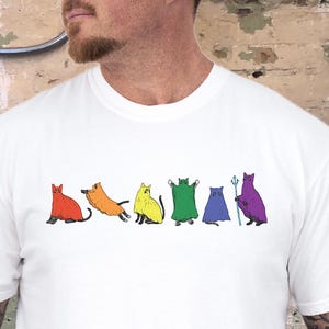 Peut inclure: T-shirt blanc avec un motif color&eacute; de chats stylis&eacute;s dans diff&eacute;rentes poses. Chaque chat a un design unique. Le mot "WHITE" est imprim&eacute; en bas &agrave; droite du t-shirt. V&ecirc;tement d&eacute;contract&eacute;.