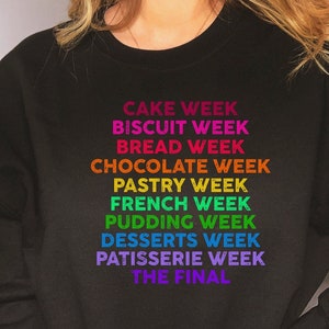 May include: Black sweatshirt with a rainbow-colored graphic that reads "Cake Week", "Biscuit Week", "Bread Week", "Chocolate Week", "Pastry Week", "French Week", "Pudding Week", "Desserts Week", "Patisserie Week", and "The Final".