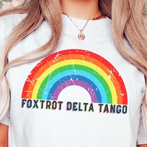 May include: White t-shirt with a rainbow graphic and the text "FOXTROT DELTA TANGO" printed on the front.