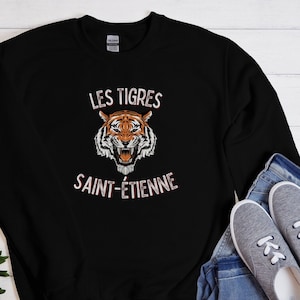 May include: Black sweatshirt with a white graphic of a tiger with the text "LES TIGRES SAINT-ETIENNE" on it.