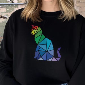 May include: Black sweatshirt with a rainbow geometric cat design. The cat is sitting with its tail curled around its body.
