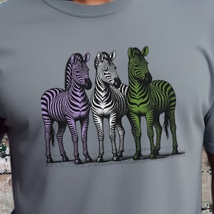 May include: A gray t-shirt with a graphic of three zebras. The zebras are purple, white, and green.
