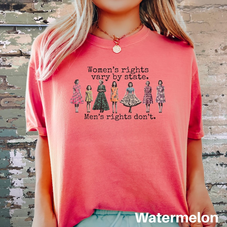 Puede incluir: Una camiseta de color sand&iacute;a con el texto "Women's rights vary by state. Men's rights don't." impreso en negro. La camiseta presenta una ilustraci&oacute;n de siete figuras con vestidos. La palabra "Watermelon" est&aacute; impresa en la parte inferior.