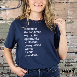 May include: A navy blue t-shirt with white text that reads "remember the two times we had the opportunity to elect an overqualified woman as our president?"