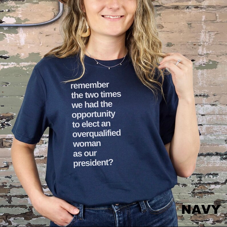 May include: A navy blue t-shirt with white text that reads "remember the two times we had the opportunity to elect an overqualified woman as our president?"