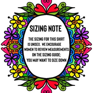 以下が含まれることがあります： 「SIZING NOTE」のテキストが入った白い楕円形。カラフルな花のボーダーで囲まれています。楕円内のテキストは、シャツがユニセックスであることを示し、サイズガイドで測定値を確認することを推奨しています。