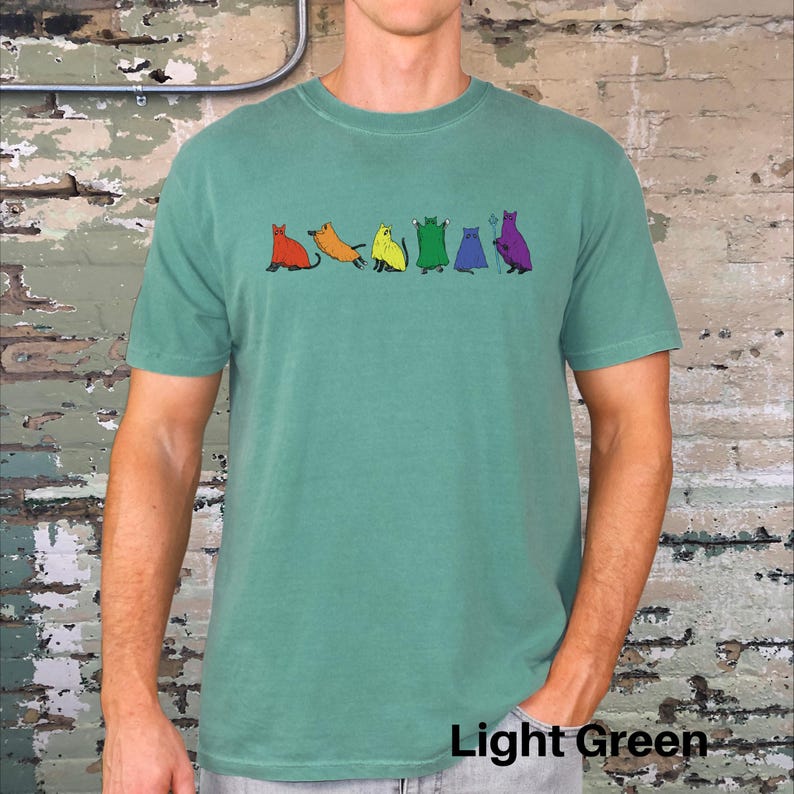 Peut inclure: T-shirt vert clair avec une rang&eacute;e de chats de dessin anim&eacute; color&eacute;s. Les chats sont rouges, oranges, jaunes, verts, bleus et violets. Le texte "Light Green" est en bas de l'image.