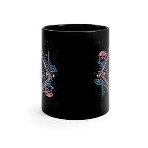 May include: Black ceramic mug with a geometric design featuring pink and blue roses. The design includes a triangle with a star inside and the words "Let it be" written in a script font.