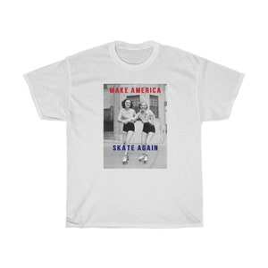 May include: White t-shirt featuring a black and white image of two women roller skating. The text "MAKE AMERICA" is in red above the image, and "SKATE AGAIN" is in blue below the image.