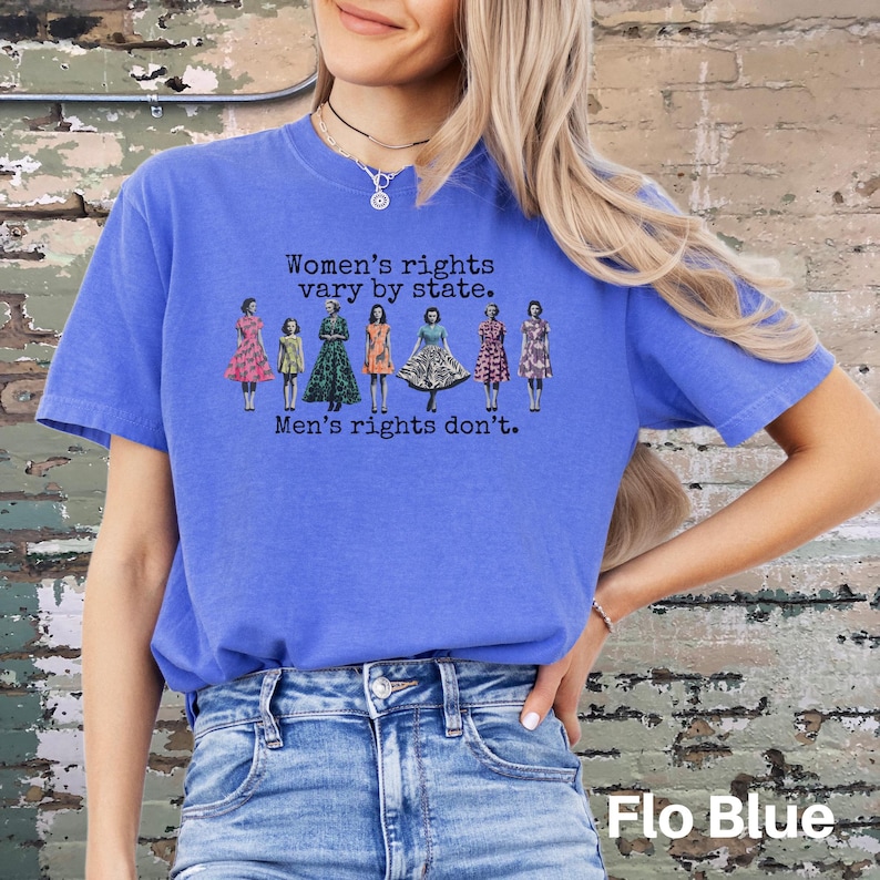 Puede incluir: Camiseta azul con el texto "Women's rights vary by state. Men's rights don't." y un gr&aacute;fico de mujeres con vestidos. La camiseta es de color azul liso.