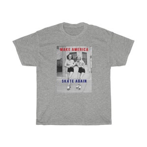May include: A gray t-shirt featuring a black and white image of two women roller skating. The image has the text "MAKE AMERICA" in red above the image and "SKATE AGAIN" in blue below the image.