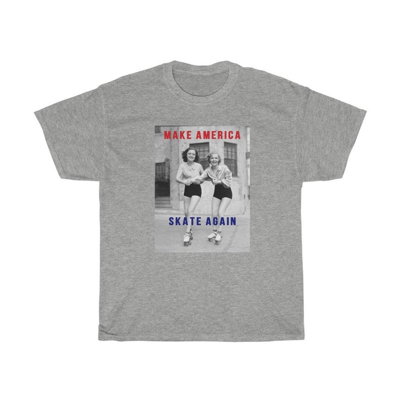 May include: A gray t-shirt featuring a black and white image of two women roller skating. The image has the text "MAKE AMERICA" in red above the image and "SKATE AGAIN" in blue below the image.