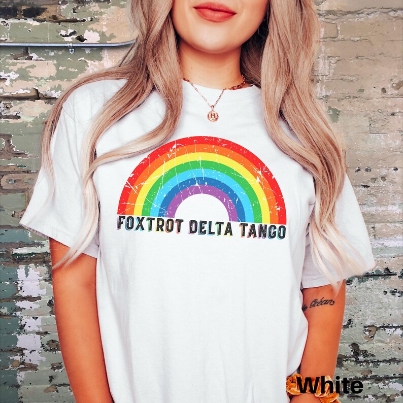 May include: White t-shirt with a rainbow graphic and the text "FOXTROT DELTA TANGO" printed on the front.