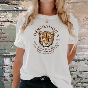 Puede incluir: Camiseta blanca con un gr&aacute;fico marr&oacute;n y naranja de una cabeza de leopardo. El gr&aacute;fico est&aacute; rodeado de texto que dice "Generation X 1965 - 1980 Less Cranky Than Boomers Less Whiny Than Millennials Cooler Than Both"