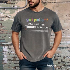 May include: A dark gray t-shirt with the text "got polio*? Me neither. Thanks science." in colorful letters. The text is followed by a list of diseases, including diphtheria, pertussis, tetanus, measles, mumps, rubella, HPV, Haemophilus, pneumococcus, hepatitis A, hepatitis B, and varicella.