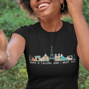 May include: A black t-shirt with a graphic of the Paris skyline and the text "Paris is calling and I must go".
