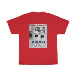 May include: A red t-shirt featuring a black and white image of two women roller skating. The image has the text "MAKE AMERICA" in red and "SKATE AGAIN" in blue.