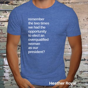 May include: A blue heather t-shirt with white text that reads "remember the two times we had the opportunity to elect an overqualified woman as our president?" The text is centered on the shirt. The bottom of the shirt has the text "Heather Royal" in white.