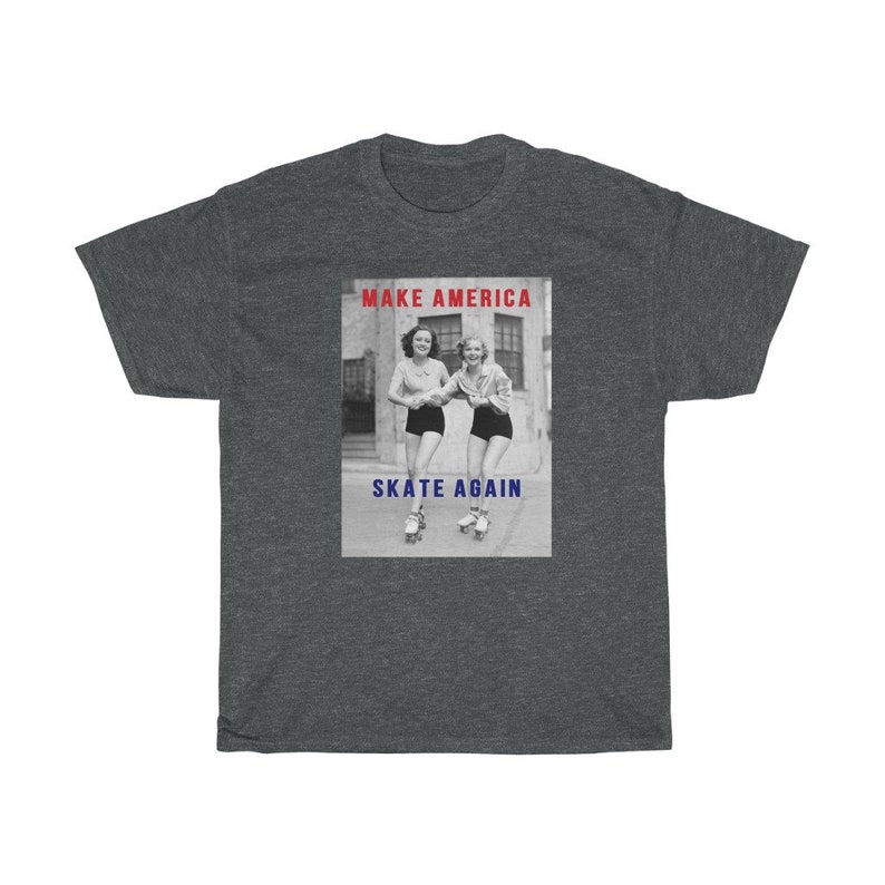 May include: Dark gray t-shirt featuring a black and white image of two women roller skating. The text "MAKE AMERICA" is above the image in red, and "SKATE AGAIN" is below in blue.