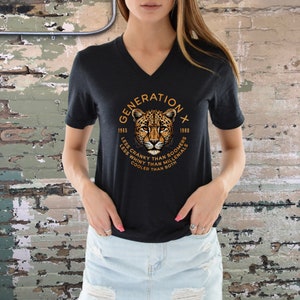 May include: Black v-neck t-shirt with a graphic of a leopard and the text "GENERATION X 1965 - 1980 LESS CRANKY THAN BOOMERS LESS WHINY THAN MILLENIALS COOLER THAN BOTH"