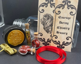 May include: A glass jar with a gold wax seal and a red ribbon. The jar contains three small glass bottles filled with red and gold glitter. Two cards with a lion illustration and the words "Courage, Daring, Chivalry, Bravery" are on the table. A red ribbon is also on the table.