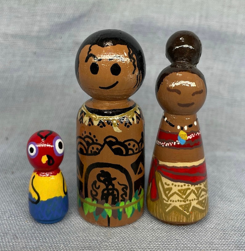 May include: Three wooden peg dolls, one red with a yellow and blue design, one brown with black and white designs and a green lei, and one brown with a red and gold design and a gold necklace.