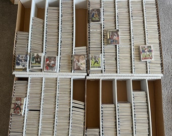 May include: A white storage box with multiple rows of clear plastic sleeves containing sports trading cards. The cards feature images of football players.