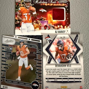 May include: Three football trading cards featuring Denver Broncos players. One card is a "Holiday Suit" card with RJ Harvey. Another card features Bo Nix. The third card shows Devaughn Vele, with stats and a limited edition number.